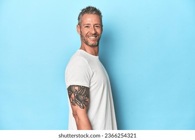 Middle-aged man posing on blue studio backdrop - Powered by Shutterstock