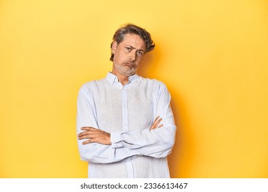 Middle-aged man posing on a yellow backdrop tired of a repetitive task. - Shutterstock ID 2336613467