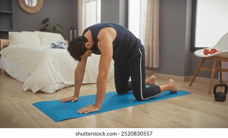 Middle-aged man practicing yoga on a blue mat in a modern bedroom interior. - Powered by Shutterstock