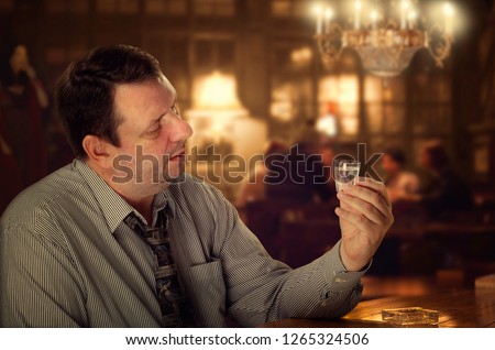 Уже поднабравшись слегка в баре мужик внимательно смотрит на стопку водки