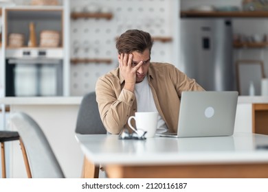 Middle-aged Man Sitting In Front Of Laptop In Dining Room And Feels Stressed After Realized How Much Work He Has And That He Will Not Be Able To Go On Vacation.