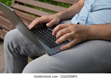 Middle-aged man sitting on a park bench working on a laptop - Powered by Shutterstock