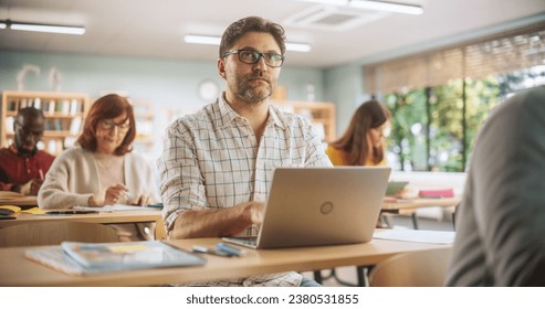 Middle-Aged Man Studying in Classroom, Using Laptop Computer to Write Down Lecture Notes. Group of People Taking a Workshop on Improving Professional Soft Skills. Adult Education Center Concept - Powered by Shutterstock