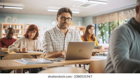Middle-Aged Man Studying in Classroom, Using Laptop to Write Down Lecture Notes. Group of People Taking a Workshop on Improving Professional Soft Skills. Adult Education Center Concept