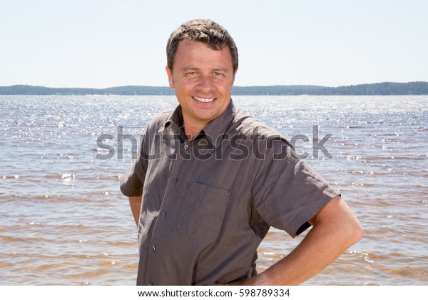 A middle-aged man tanned and beautiful in front of\
the sea or the ocean