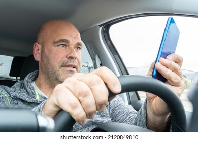 Middle-aged man using the phone while driving a car
