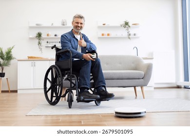 Middle-aged man using robot vacuum cleaner in living room. Clean, organized environment supports assistive lifestyle showcasing independence and technology.