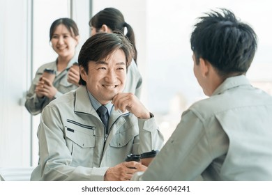 A middle-aged man in work clothes drinking coffee in the office break room
