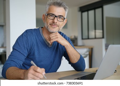 Middle-aged man working from home-office on laptop