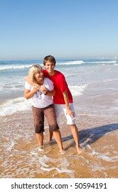 Middle-aged Mother And Teen Son Playing On Beach