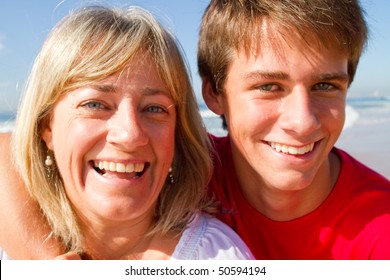 Middle-aged Mother And Teen Son Playing On Beach