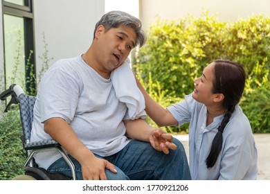 Middle-aged And Obese Men Are Paralyzed, Crooked Mouth, Crinkled Hands And Limb Weakness  In The Wheelchair And There Is A Wife Using A Towel On The Face Of Her Husband With Love And Good Hope