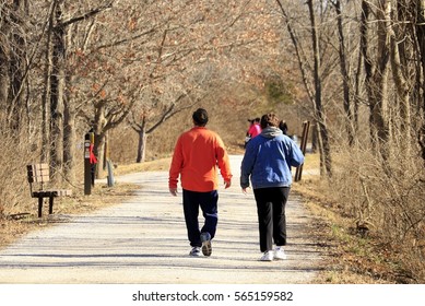 Middle-aged Overweight Couple Walking On The Trail In A Park; Midwest, Missouri