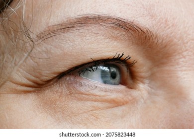 middle-aged woman does corrective eye makeup to correct the drooping eyelid. Ptosis is a drooping of the upper eyelid, lazy eye. Cosmetology and facial concept, closeup