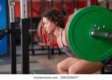 Middle-aged woman doing squats with a barbell in the gym.  - Powered by Shutterstock