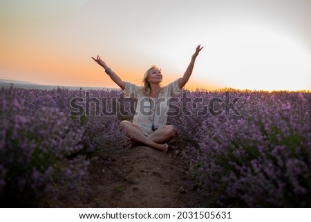 Middle-aged woman dressed boho style clothes, older female breath the healthy air in the field of lavender against the sun