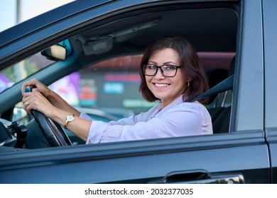 Middle-aged woman driver with glasses, female driving a car.