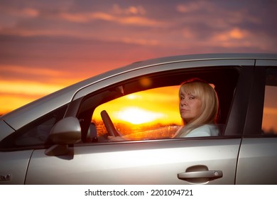 Middle-aged Woman Driving A Car Against The Sunset Sky.Stranger