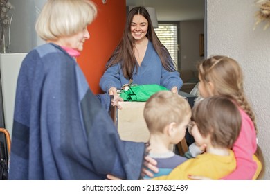 Middle-aged woman gives Ukrainian family of refugee clothes and toys to support them because they had to flee Russian attack. Humanitarian aid and helping hand from world for Ukraine during the war - Shutterstock ID 2137631489
