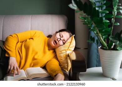 Middle-aged woman in glasses fell asleep while reading book at home, female sleeping with open mouth on sofa near coffee table with houseplant in living room. Sleep deprivation - Shutterstock ID 2122133960