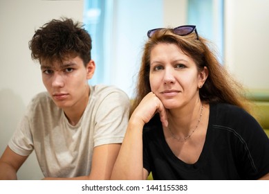 A Middle-aged Woman With His Teenage Son Resting At The Cafe And Talking About Teenage Problems. Mom Has Fun, But The Son Is Very Serious