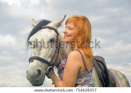 Middle-aged woman with a horse by the lake