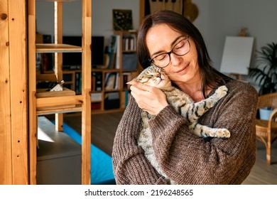 Middle-aged woman hugging cute tabby cat in indoor scene. Human-animal relationships. Funny home pet. Homeless pets. - Powered by Shutterstock