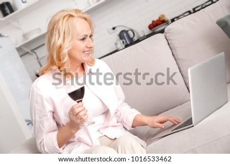 Two women enjoying wine while using laptop outdoors