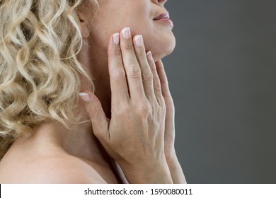 A middle-aged woman looking at her face in the mirror