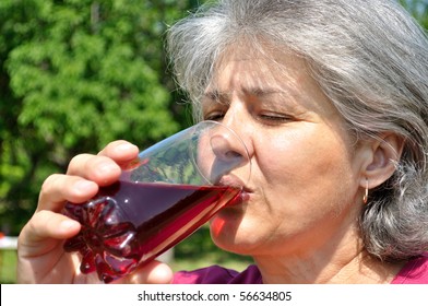 Middle-aged Woman With Pleasure Drinking Cherry Juice