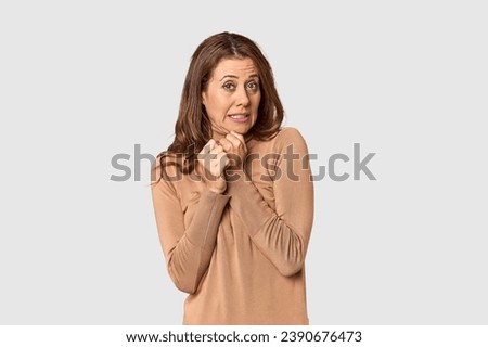 Middle-aged woman portrait in studio setting scared and afraid.