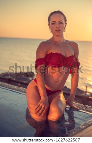 Middle-aged woman in red bikini in a pool water