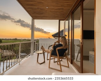 Middle-aged woman relaxing in a chair on a balcony with view on rice terrace at sunset - Powered by Shutterstock