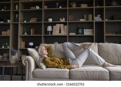 Middle-aged woman relaxing on cozy sofa in fashionable living room looking carefree enjoy repose at modern home, breath fresh conditioned air inside cozy flat. Free time, daydreaming, tenant concept - Shutterstock ID 2166522761