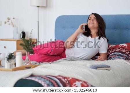 middle-aged woman resting at home. lady relaxed in bed talking on the phone with her boyfriend