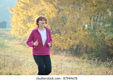 Middle-aged Woman Running Through The Woods