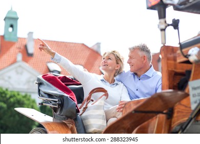 Middle-aged woman showing something to man while sitting in horse cart