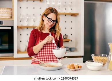 A Middle-aged Woman Stirring And Making A Dinner In Kitchen At Her Home.