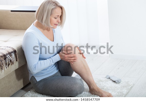 Middle-aged woman\
suffering from pain in leg at home, closeup. Physical injury\
concept. Ankle pain, painful\
point.