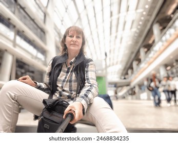 Middle-Aged Woman Taking Selfie at Airport Before Departure. A middle-aged woman captures selfie in an airy airport terminal - Powered by Shutterstock