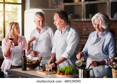 Middle-aged Woman Telling Stories To Elderly Friends While Cooking Lunch