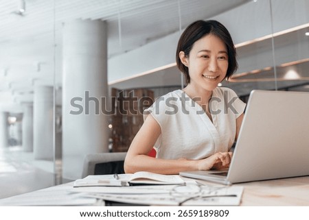 Middle-aged woman using computer technology for financial marketing work online. Busy mature Asian professional businesswoman analyst working concentrated on laptop pc at desk in office. Copy space