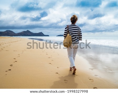 Middle-aged woman walking on beach 