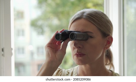 A Middle-aged Woman Is Watching Closely While Looking Through Optical Binoculars. Follow Someone. Gaze.