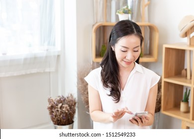 Middle-aged Women Asian Happy Using Smart Phone In A Room With Nature Sunlight At Home. Technology Communication Concept