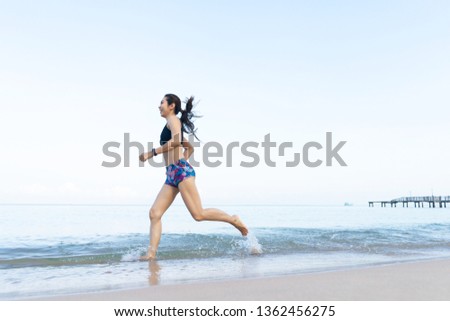 Middle-aged women who is running by the sea with blue skies and clean white sand. good health and happiness concept.