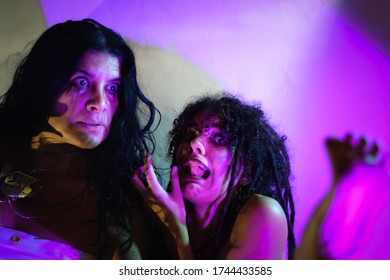 A middle-aged and a young model scared, looking at a foot with magenta light