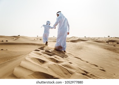 Middle-eastern father and son wearing arab traditional kandura spending time in the desert, Dubai - Powered by Shutterstock