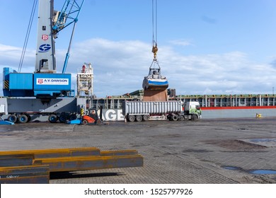 Middlesbrough, Teesside / UK - October 08 2019: Illustrative Editorial, Mobile Crane With Large Bucket Unloading Aggregate From A Cargo Ship Into A Semi Truck Tipper At The Riverside In Middlesbrough.