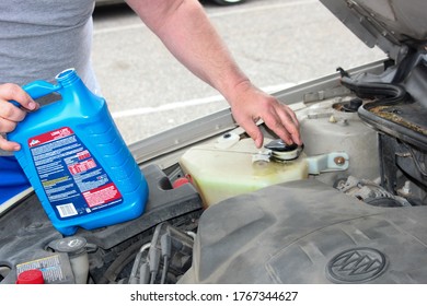 MIDDLETOWN, NY, UNITED STATES - May 04, 2020: A Man's Arm Is Replacing The Cap On Coolant Tank Under His Car Hood. He Preformed Diy Car Maintenance By Filling Tank With New PEAK Brand Antifreeze.